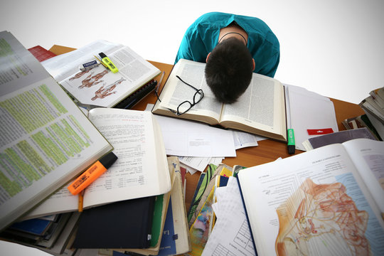 Medical student sit at the desk, study medical literature, take an exam. Stressed and tired young male