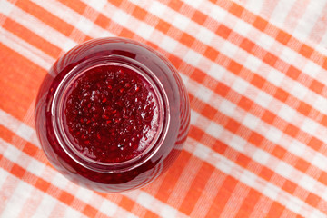 Jar of berry jam on table background. Top view.