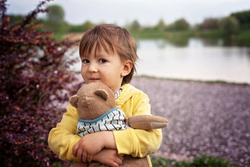 Adorable little boy, holding toy friend in a park