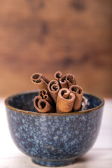Bunch of cinnamon sticks in the bowl on wooden background