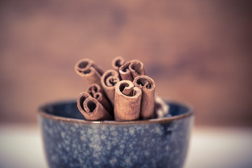 Bunch of cinnamon sticks in the bowl on wooden background