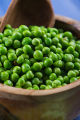 Wooden bowl with fresh sweet petite peas and scoop