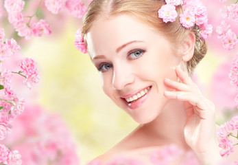 Beauty face of young happy beautiful woman with pink flowers in