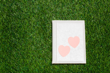 White book with two hearts lying on the grass