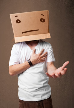 Young man gesturing with a cardboard box on his head with straig