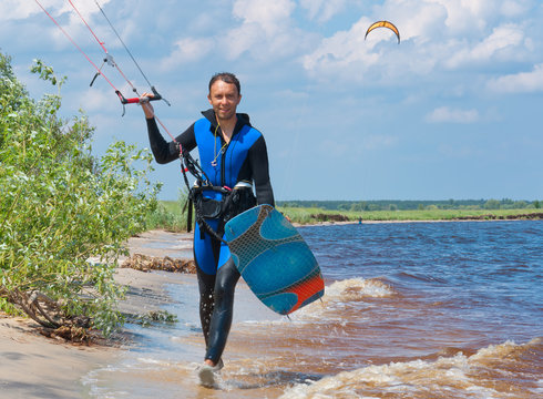Kite surfer walking on the beach with surfboards