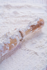 close up view on wooden rolling pin white natural flour food and
