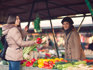 Smiling young woman choosing vegetables at the market place