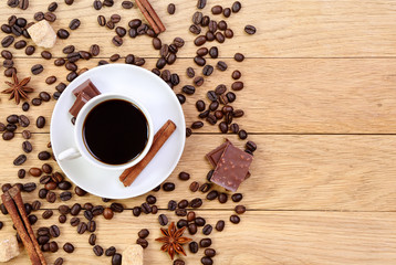 Cup of coffee, chocolate, sugar, spices and coffee beans on a wo