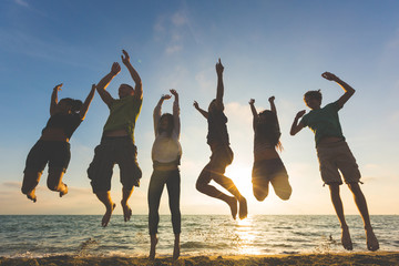 Multiracial group of people jumping at beach