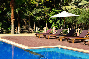 Swimming pool with chairs and umbrella.