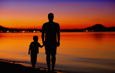 Fototapeta na wymiar father and son near the water edge at sunset