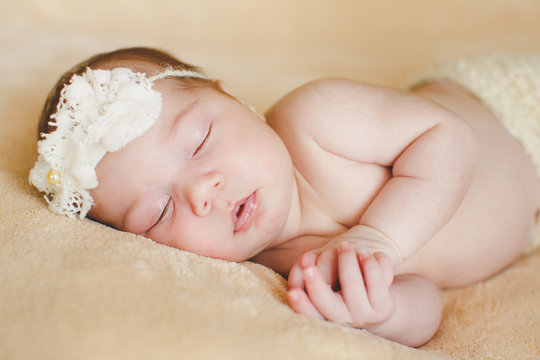 Photo of a newborn baby curled up sleeping on a blanket