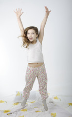 Little girl jumping on bed isolated