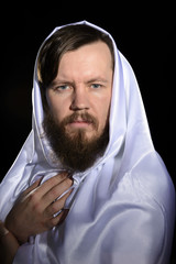 portrait of a bearded man in the studio in a white cape