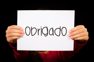 Child holding sign with Portuguese word Obrigado - Thank You