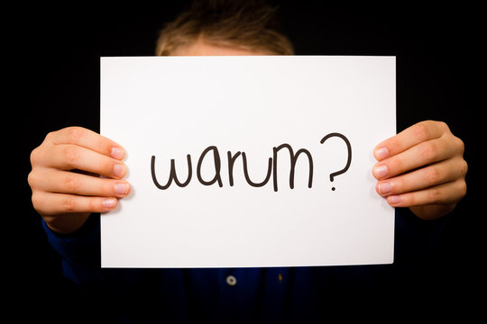 Child holding sign with German word Warum - Why