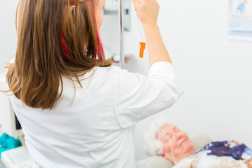 Obraz na płótnie Canvas Doktor legt Klinik Seniorin einen Tropf 
