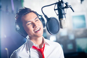 Asian male singer producing song in recording studio