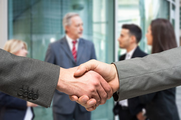 Business handshake. People talking in the background