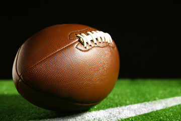 American football on green grass, on black background