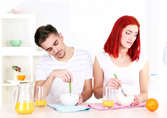 Obraz na płótnie Canvas Sleepy couple has breakfast in kitchen