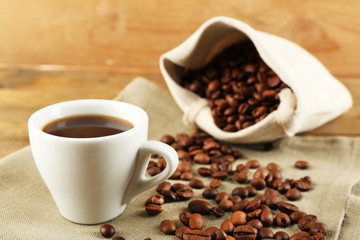 Cup of coffee with beans on rustic wooden background