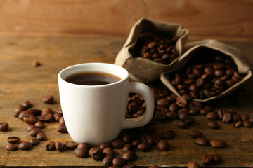 Cup of coffee with beans on rustic wooden background