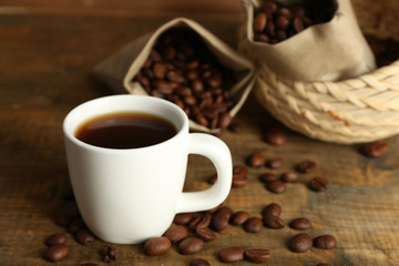 Cup of coffee with beans on rustic wooden background