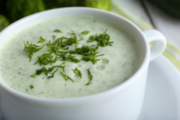 Cucumber soup in bowl on color wooden table background