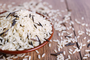 Grain of rice on plate on wooden background
