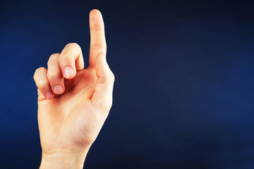 Male hand pointing up on dark blue background