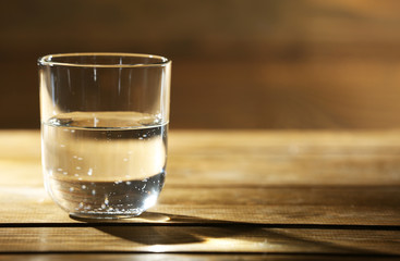 Glass of clean mineral water on rustic wooden background