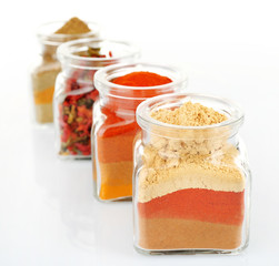 Different kinds of spices in glass bottle isolated on white