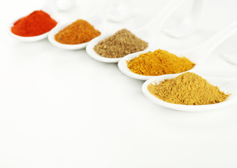 Different kinds of spices in ceramics spoons isolated on white
