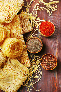 Different dry instant noodles with spices on wooden background