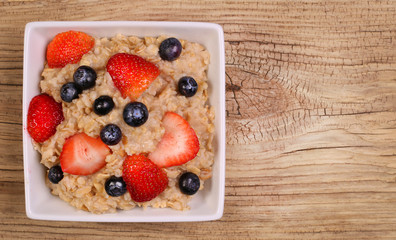 Oatmeal with berries on wooden background