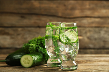 Glasses with fresh organic cucumber water on wooden table