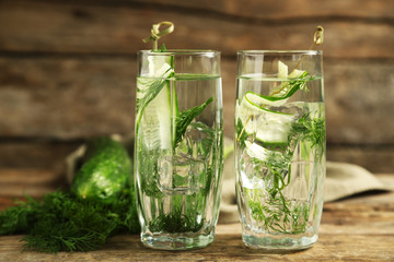 Glasses with fresh organic cucumber water on wooden table