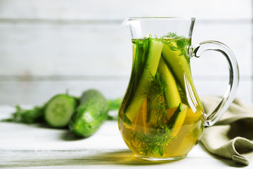 Glass ewer with fresh organic cucumber water on wooden table