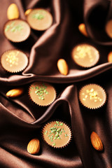 Tasty chocolate candies on satin cloth, close up