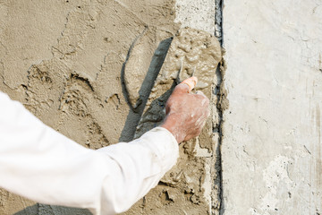 plasterer concrete worker at wall of house construction