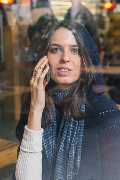 Beautiful girl talking on phone behind a window
