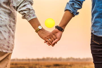 couple holding hands in sunset background