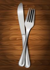 Fork and knife on wooden background for your design