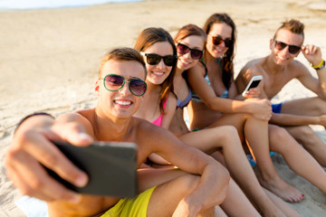 friends with smartphones on beach