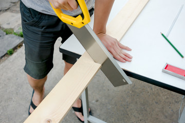 Carpenter working on a hand saw cutting wood board