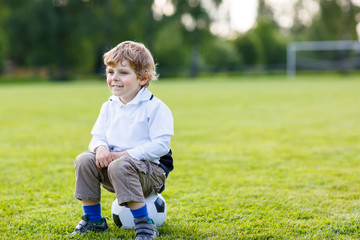 Fototapeta premium Blond boy of 4 resting with football on football field