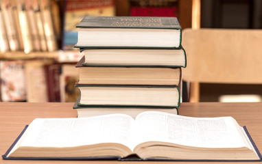 The open book and pile of books in library
