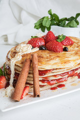 White plate full of pancakes with raspberries strawberries blueb